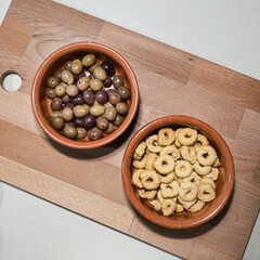 olive e taralli in due ciotole in terracotta sopra una tavola di legno