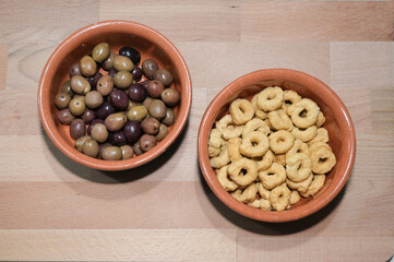 olive e taralli in due ciotole in terracotta sopra una tavola di legno