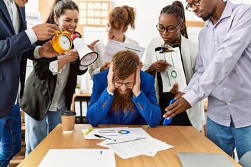 Group of business workers screaming to stressed partner at the office.