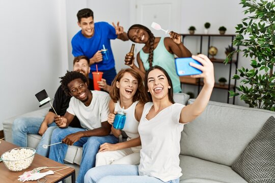 Group of young friends using funny costume accessories making selfie by the smartphone at home.