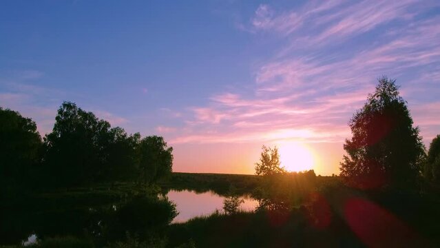 Beautiful pink sunset over a calm river, summer landscape.