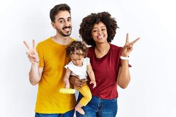 Interracial young family of black mother and hispanic father with daughter smiling with happy face...