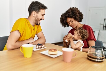 Fototapeta na wymiar Couple and daughter having breakfast sitting on table at home