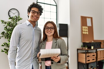 Obraz premium Two business workers smiling happy holding clipboard standing at the office.