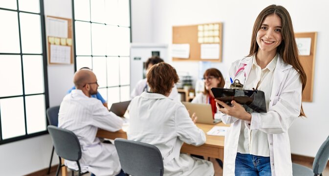 Group of young doctor working at the clinic office. Woman smiling happy writing on clipboard. - Powered by Adobe
