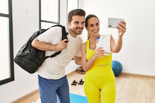 Young hispanic sporty couple making selfie by the smartphone at sport center.