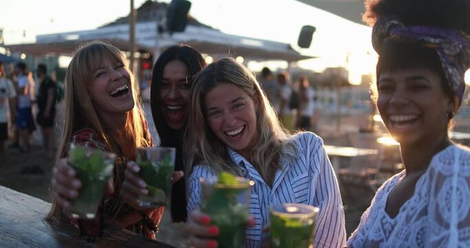 Happy multiracial girls having fun drinking mojitos at beach party outdoor