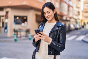 Young woman smiling confident using smartphone at street