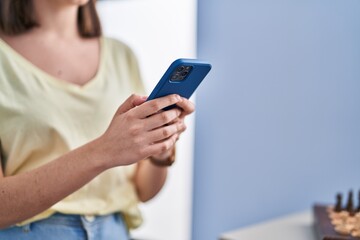 Young hispanic woman using smartphone at home