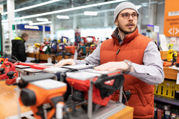 a man chooses an electric planer in a building and finishing materials store