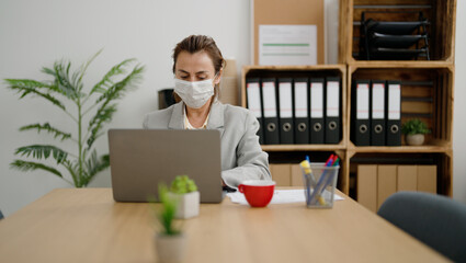 Middle age hispanic woman business worker wearing medical mask working at office