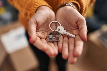 Young latin woman holding key of new house at new home