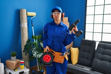 Young hispanic technician working at home renovation puffing cheeks with funny face. mouth inflated...