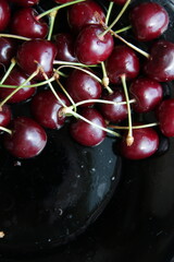 Ripe juicy cherries on an elegant black plate. Vintage style.