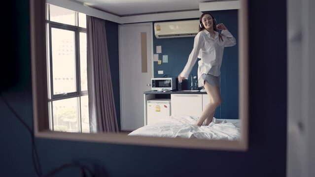 woman enjoyed listening to music and dancing on bed. slow motion Lady spun around happily celebrating.

