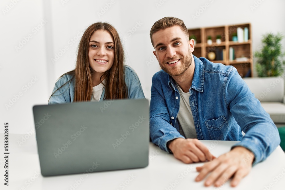 Sticker young caucasian couple smiling happy using laptop at home.