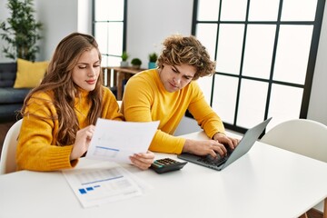 Young caucasian couple smiling confident doing family accounting using laptop at home