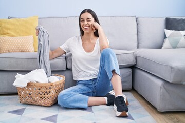 Young brunette woman doing laundry at home winking looking at the camera with sexy expression,...