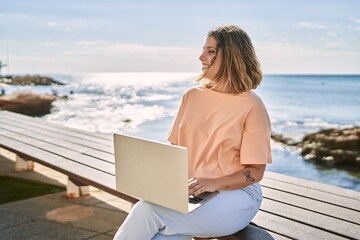 Young hispanic woman smiling confident using laptop at seaside