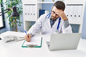 Young hispanic man wearing doctor uniform stressed working at clinic