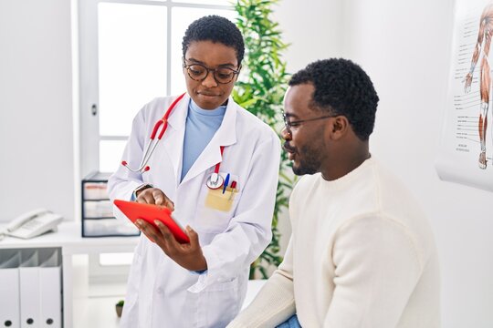 Man And Woman Doctor And Patient Having Medical Consultation Using Touchpad At Clinic