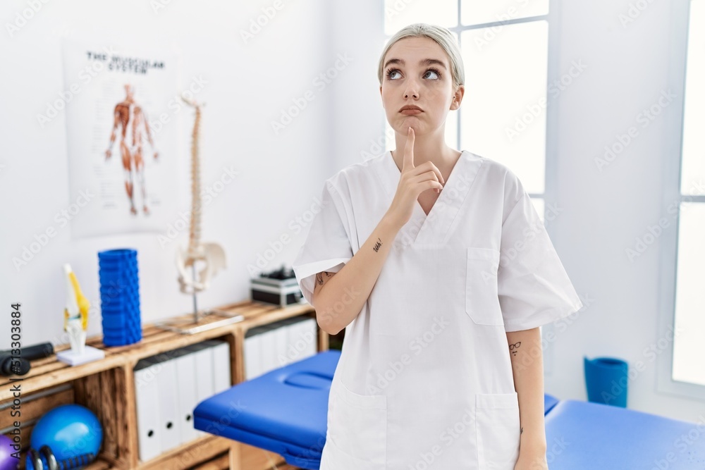 Sticker young caucasian woman working at pain recovery clinic thinking concentrated about doubt with finger 