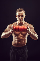 Power, strength, excellent body, bodybuilding, sports concept. Young handsome muscular fit man demonstrating perfect body and hold circles of cheese in orange wax