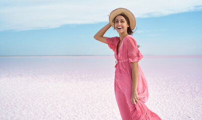 Beautiful excited woman emotionally smile, wearing elegant pink dress and hat, enjoying vacation at beach of pink lake. Ukraine Syvash lake - 513304088
