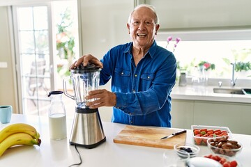 Senior man smiling confident using blender at kitchen