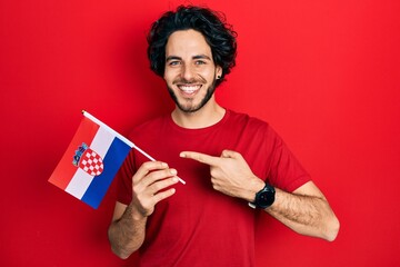 Handsome hispanic man holding croatia flag smiling happy pointing with hand and finger