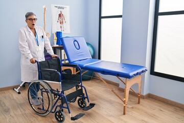 Middle age woman with wheelchair scared and amazed with open mouth for surprise, disbelief face
