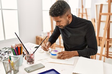 Young african american artist man concentrated painting pottery at art studio.