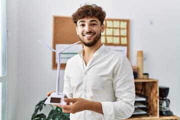 Young arab man smiling confident holding. windmill at office