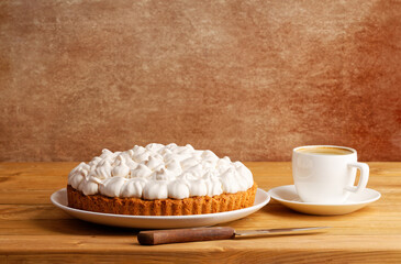 Homemade berry pie decorated with meringue and a cup of coffee on a wooden table. Copyspace.