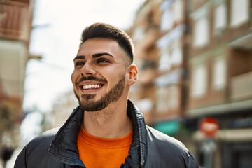 Fototapeta premium Handsome hispanic man with beard smiling happy and confident at the city wearing winter coat