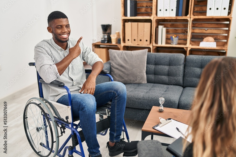 Sticker african american man doing therapy sitting on wheelchair cheerful with a smile of face pointing with