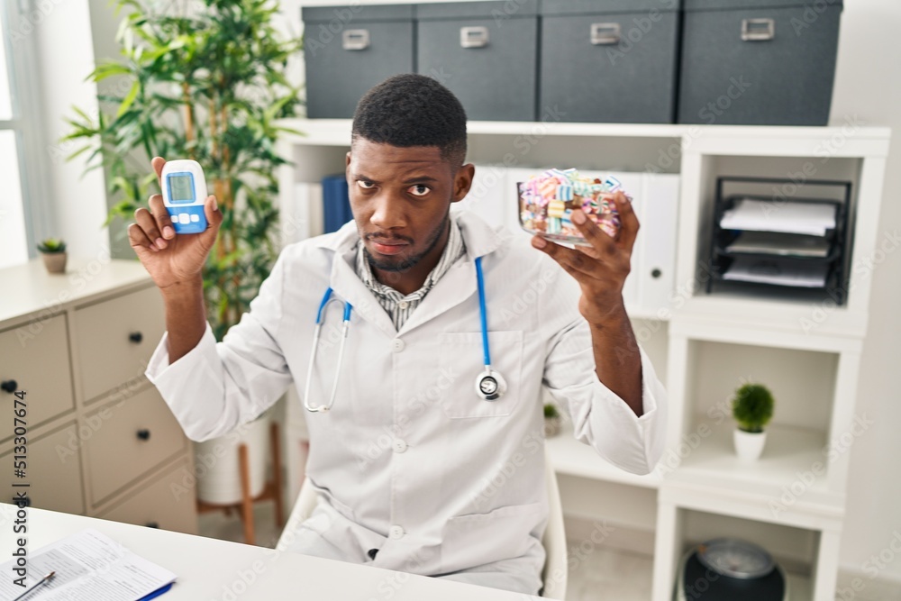 Wall mural African american doctor man using glucose meter skeptic and nervous, frowning upset because of problem. negative person.