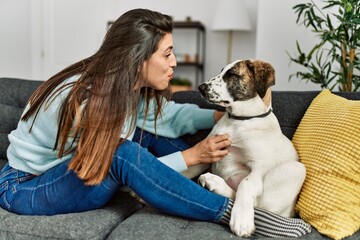 Young woman hugging dog sitting on sofa at home