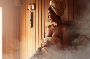Young woman relaxing and sweating in hot sauna wrapped in towel. Girl In Sauna. Interior of Finnish...