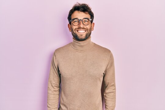Handsome man with beard wearing turtleneck sweater and glasses with a happy and cool smile on face. lucky person.