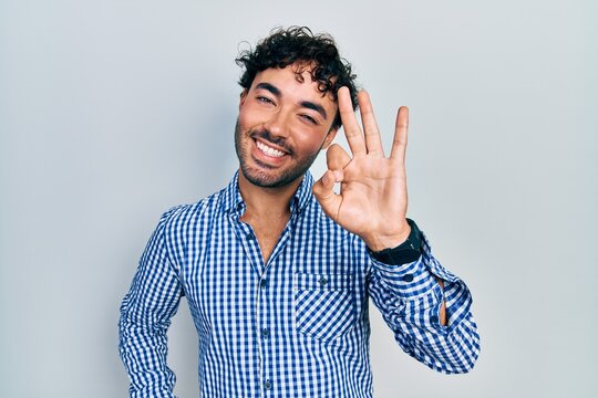 Young hispanic man wearing casual clothes showing and pointing up with fingers number three while smiling confident and happy.