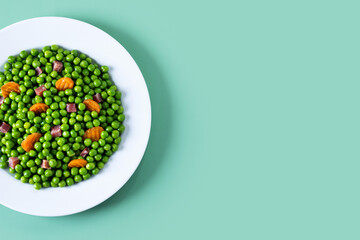Green peas, serrano ham and carrot on green background. Top view. Copy space