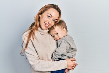 Young caucasian woman holding and hugging her son with love. Family of two bonding together. Mother holding infant toddler