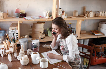 a woman master in the production of wooden toys takes orders by writing in a notebook.