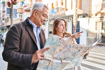 Middle age man and woman couple smiling confident looking city map at street