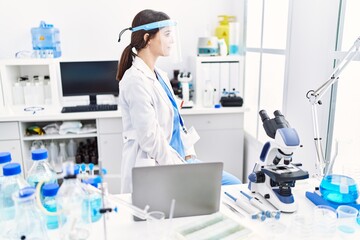 Young hispanic woman wearing scientist uniform looking to side, relax profile pose with natural face with confident smile.