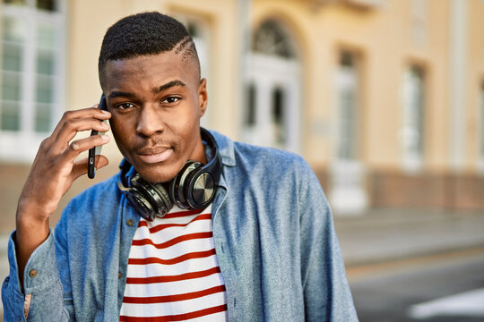 Young african american man with serious expression talking on the smartphone at the city.