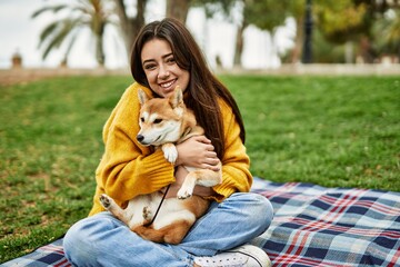 Beautiful young woman hugging happy shiba inu dog at park