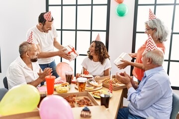 Group of middle age friends celebrate birthday giving gifts at home