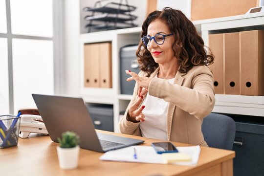 Middle age hispanic woman doing video call using sign language at the office